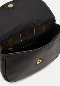 Czarna skórzana torebka z klapką i złotymi okuciami. Wnętrze wyłożone jest gładką tkaniną w kratę oraz posiada kieszeń na zamek.