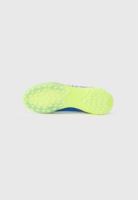 Suela de zapatilla deportiva con un diseño de goma texturizada en un brillante color amarillo con acentos en verde, una plantilla azul y un diseño moldeado para mejorar la tracción.