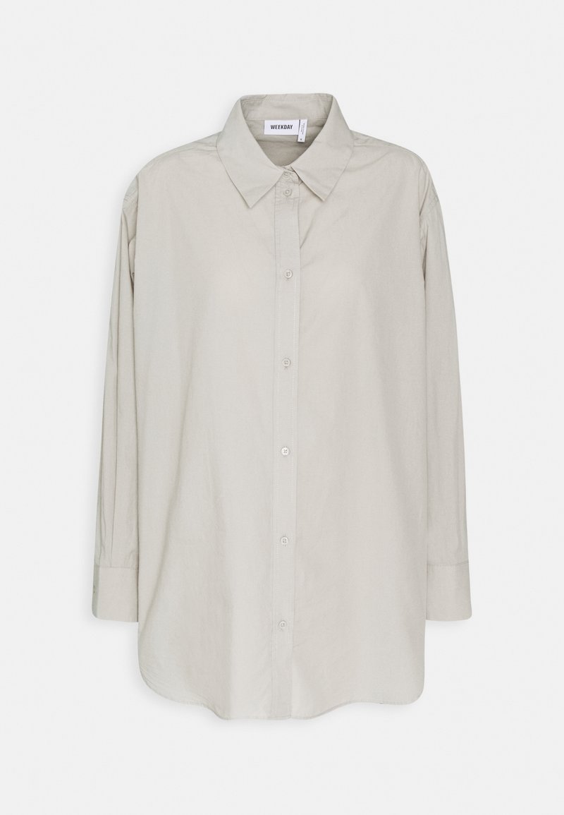 Chemise boutonnée gris clair avec un col classique, des manches longues et une texture douce et lisse. Présente un ourlet droit et une patte de boutonnage visible.