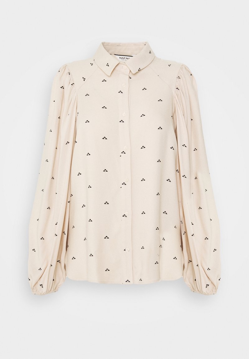 Blouse crème avec un devant boutonné, de longues manches bouffantes et un motif de petits triangles noirs. Texture de tissu lisse.