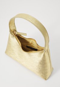 Gold handbag with a textured metallic finish, zip closure, and a curved handle. Interior lined in beige fabric with brand label visible.