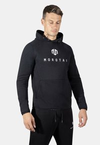 Sudadera negra de tejido suave con un bolsillo canguro, que presenta un prominente logo blanco "MOROTAI" en el pecho y capucha ajustable con cordón.