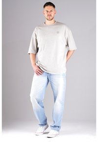 Gray oversized T-shirt with short sleeves, paired with light blue jeans. White sneakers complete the casual look. Simple design with no patterns.