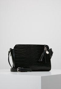 Sort krokodilleder-embossed håndtaske med en strømlinet rektangulær form. Har en aftagelig rem, frynse-detaljer og hardware i sølvfarve.