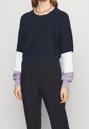 Maglione lavorato a maglia blu navy con maniche a blocchi di colore bianco e lavanda. Presenta un collo rotondo e dettagli a coste nell'orlo e nei polsini.