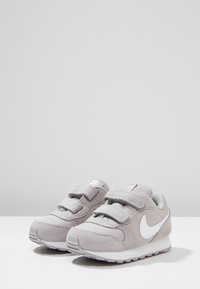 Šedé tenisky Nike s svrchním materiálem z jemné kůže a síťoviny, s dvěma suchými zipy, bílými akcenty a texturovanou gumovou podrážkou.
