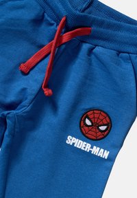Siniset puuvillajoggerit, joissa on punainen nyöri, ja jotka sisältävät brodeeratun Spider-Man-logon sekä "SPIDER-MAN"-tekstin valkoisena.