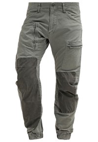 Pantalon cargo gris avec poignets élastiques, renforts sombres au niveau des genoux et poches zippées sur la cuisse et la partie supérieure de la jambe.