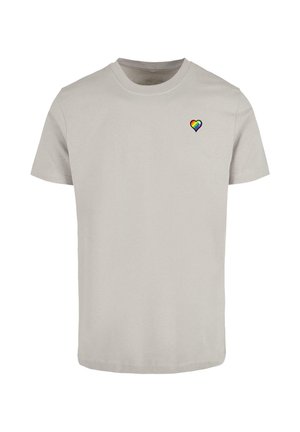 Ljust grå bomullströja med korta ärmar och rund halsringning, med ett litet regnbågs-hjärta-emblem på vänster bröst.