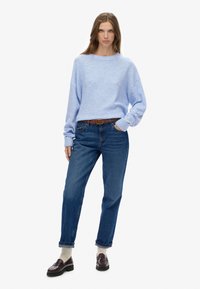Jasnoniebieski sweter z okrągłym dekoltem, o luźnym kroju i ściągaczami na rękawach, zestawiony z ciemnoniebieskimi jeansami i brązowymi mokasynami. Teksturowana bawełniana mieszanka.