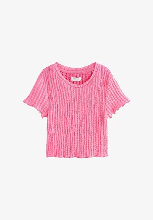 Svetlo roza kratka majica s kratkimi rokavi, teksturirana, z okrolim izrezom in nežnimi nabranimi robovi, položena na ravno belo podlago.