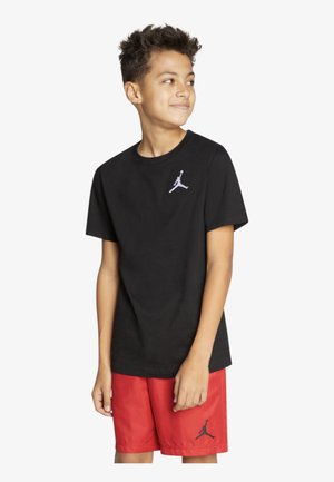 T-shirt in cotone nero con un piccolo logo bianco di Jordan sul lato sinistro del petto, abbinata a pantaloni corti rossi con un logo nero di Jordan.