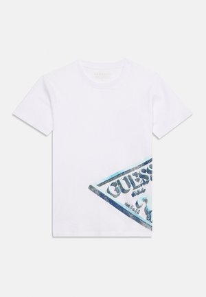 Hvid T-shirt med korte ærmer med en diagonal blå og sort Guess-logo på den nederste højre side.
