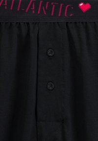 Czarne bawełniane męskie szorty z paskiem w paski ozdobionym napisem „ATLANTIC” i grafiką serca. Dwa guziki i przeszycie na kieszeni.