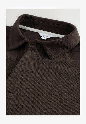Donkerbruine polo met een gestructureerde stof, een kraag, een knoopsluiting en een klein logolabel op de hals.
