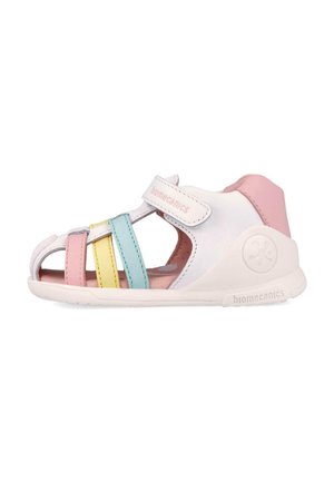 Sandalia blanca para niño pequeño con tacón rosa, correa ajustable y tiras en tonos pastel rosa, amarillo y azul en la suela blanca.