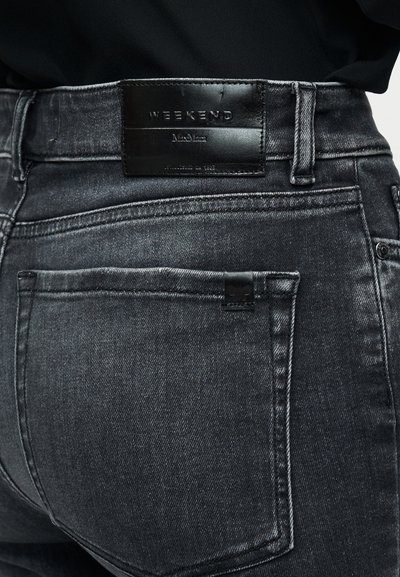 Μαύρο τζιν από denim με ξεβαμμένο φινίρισμα, με δερμάτινη ετικέτα στη μέση και πίσω τσέπες με διακριτική ραφή.