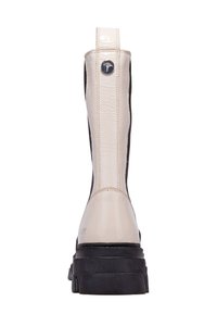 Bota beige brillante hasta la rodilla con paneles laterales elásticos negros, una suela texturizada y un detalle metálico del logo en la parte trasera.