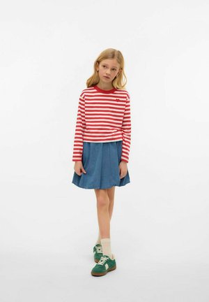 Rode en witte gestreepte blouse met lange mouwen, blauwe spijkerrok, groene sneakers, crèmekleurige sokken. Casual outfit met eenvoudige patronen.