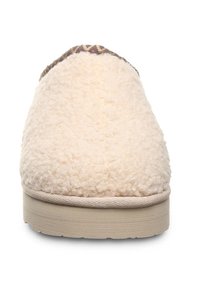 Cream-colored slippers with a textured, fuzzy upper and a contrasting patterned trim. Features a flat, neutral-colored sole.