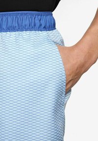 Shorts de sport bleu clair avec un motif en losange, dotés d'une taille élastique bleue et d'une poche latérale. La texture semble lisse et légère.