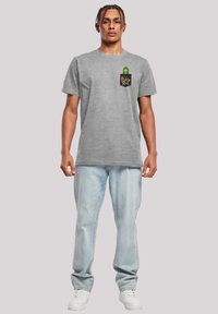 Grå bomulds t-shirt med rund hals og korte ærmer. Har et grafik af en pickle-figur med teksten "Pickle Rick" på frontlommer.