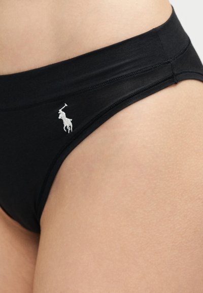 Μαύρο εσώρουχο σε στυλ μπικίνι στο ισχίο ενός ατόμου, με μικρό λευκό λογότυπο παίκτη πόλο στη αριστερή πλευρά.