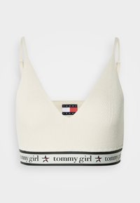 Krémový pletený bralet s nastaviteľnými ramienkami, hlbokým výstrihom do V a čiernym pásom s textom "tommy girl" a ikonami hviezd.