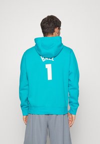 Felpa turchese con tasca a marsupio e cappuccio regolabile con cordino. Sul retro è stampato "BALL" e il numero "1" in lettering bianco in grassetto.