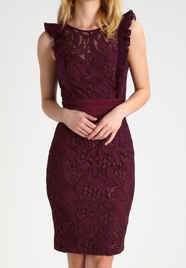 Femme portant une robe moulante sans manches en dentelle violet foncé avec des détails volantés aux épaules et un motif texturé.