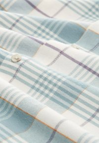 Hellblau und weiß kariertes stoff mit orangen und lila Akzenten. Das Material ist weich mit einer glatten Textur und einem sichtbaren Knopfdetail.