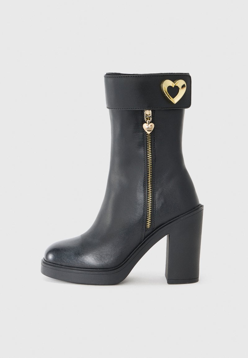 Juodai odiniai kulkšniniai batai su aukštu blokuotu kulnu, šoniniu užtrauktuku ir širdelės formos auksiniu akcentu ant krašto. Lygi tekstūra.