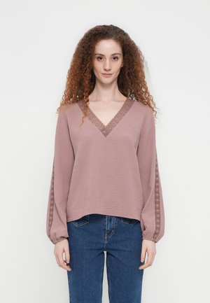 Μπλούζα σε σκόπινο ροζ χρώμα με μακριά μανίκια και V-neck, με υφή υφάσματος, κεντήματα κατά μήκος των μανικιών και άνετη γραμμή.