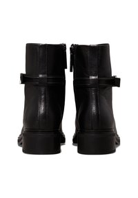 Bottines en cuir noir avec une finition texturée, dotées de deux zips et de sangles horizontales sur le dessus. Talons carrés.