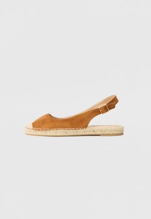 Sandale espadrille en daim marron avec orteil ouvert, bride arrière à boucle et semelle en jute tissée sur un fond neutre.