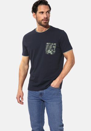 Marineblaues T-Shirt mit kurzen Ärmeln, grünem Saum und einer gemusterten Tasche mit tropischen Blättern und Blumen. Glatte Stoffqualität, lässige Passform.