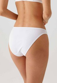 Witte katoenen slipjes met een gladde textuur, hoge beenopeningen en een minimale tailleband, die een eenvoudig, klassiek ontwerp tonen.