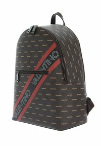 Sac à dos en cuir marron avec une sangle rouge diagonale portant "Valentino" en blanc, fermetures éclair et motifs de logo subtils.