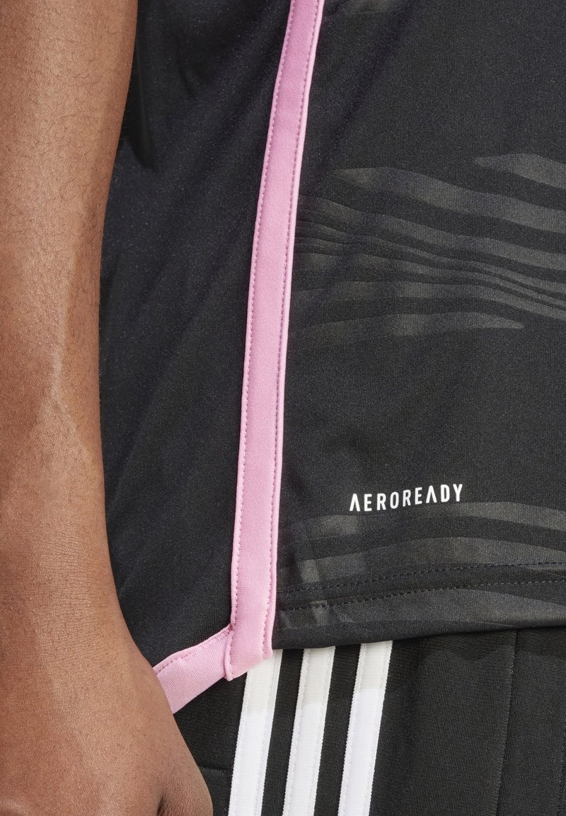 Chemise de sport noire avec accents roses, tissu texturé et logo « AEROREADY ». Présente des motifs horizontaux subtils sur le matériau.