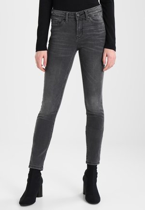 Grå denim skinny jeans med en falmet finish, klassisk fem-lomme design, bæltestropper og syningsdetaljer, båret med sorte ankelstøvler.