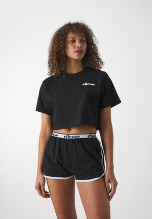 T-shirt nera corta con logo bianco, abbinata a pantaloni corti neri con rifiniture bianche e cintura con marchio. Tessuto morbido, design casual.