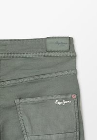 Zielone bawełniane dżinsy z tylną kieszenią i metką z logo. Szczegóły szwów wzdłuż talii i krawędzi kieszeni.