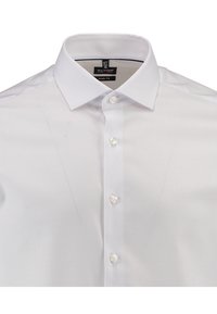 Camicia bianca con colletto classico, tessuto texturizzato e chiusura a bottoni. L'etichetta indica la taglia 15 e il design come body fit.