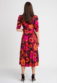 Kwiatowa sukienka midi na czarnym tle, z żywymi różowymi i pomarańczowymi kwiatami. Bufiaste rękawy, pasa w talii i zwiewna spódnica.