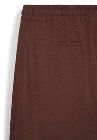 Braune Stoffhose mit elastischem Bund und einer einzelnen Gesäßtasche. Die Textur wirkt glatt und gewebt.