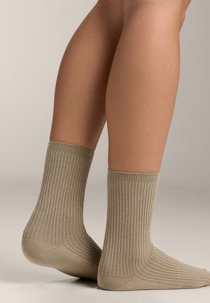 Beige ribbed cotton socks, ankle height, featuring a soft texture and reinforced heel and toe, shown on a light background.