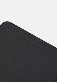 Schwarzes Lederportemonnaie mit strukturiertem Oberflächen, auf der Vorderseite mit dem eingeprägten Markennamen "LIEBESKIND BERLIN". Sauberer, rechteckiger Entwurf.