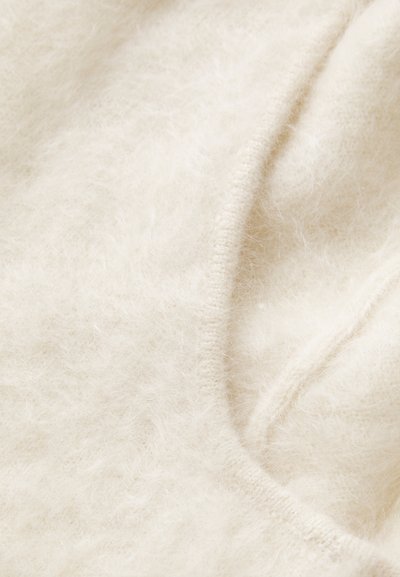 Κρεμ χρώματος, μαλακό, αφράτο ύφασμα με ορατή υφή; διαθέτει λείο, στρογγυλό άκρο και διακριτή λεπτομέρεια ραψίματος.