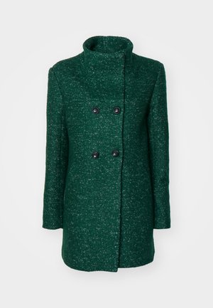 Grüner doppelt knopfbarer Mantel mit hohem Kragen, aus strukturiertem Material und zwei schwarzen Knöpfen. Gerader Schnitt und lange Ärmel.