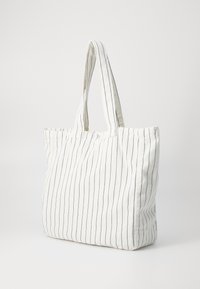 Bolsa de lona con rayas marinas sobre un fondo blanco. Cuenta con dos asas resistentes y un diseño rectangular espacioso.